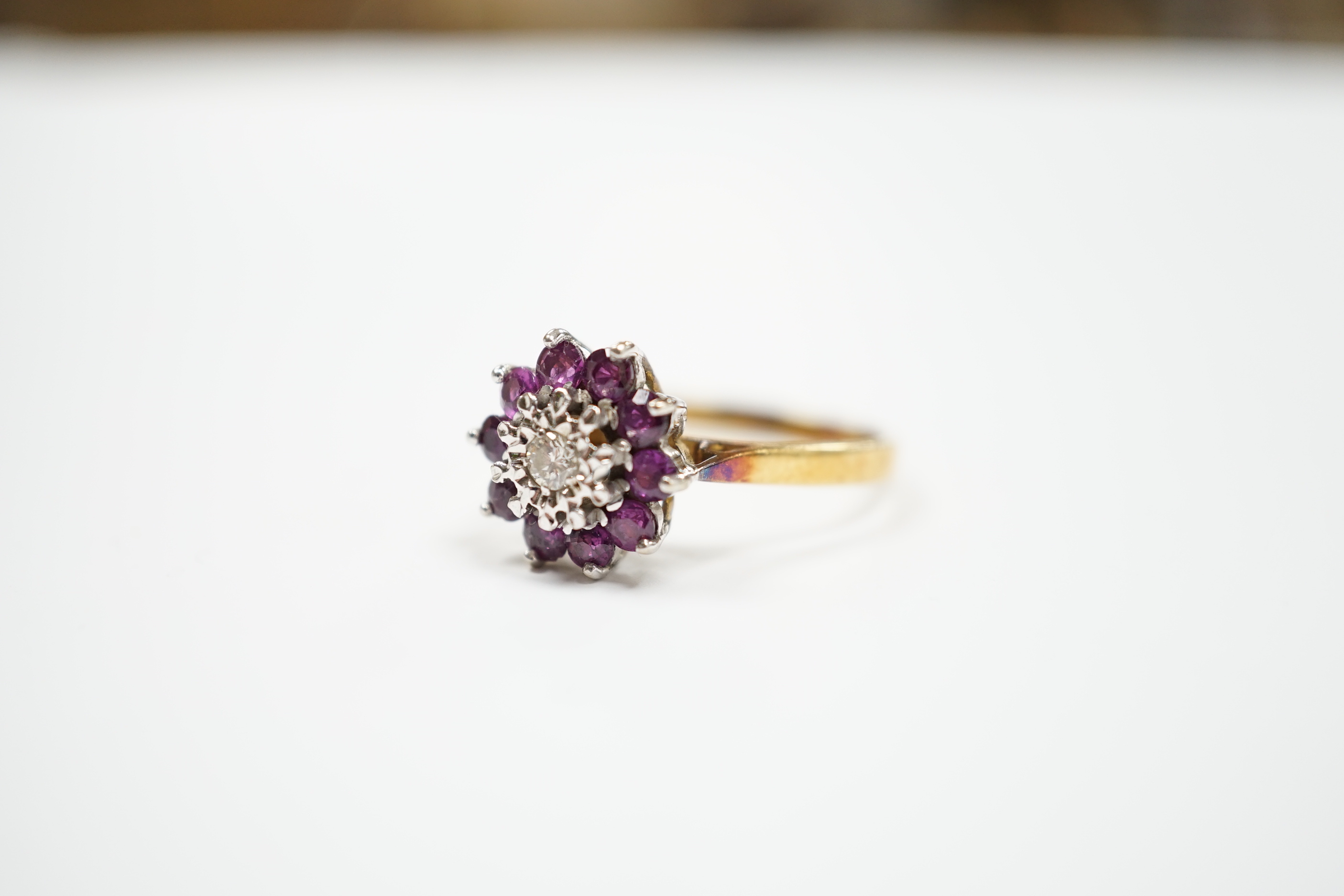 A modern 18ct gold, ruby and diamond cluster set flower head ring, size R, gross weight 4.2 grams.